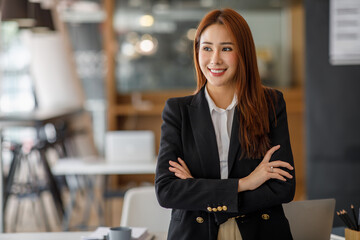 Cheerful asian businesswoman entrepreneur smiling at the camera while standing with her arms...