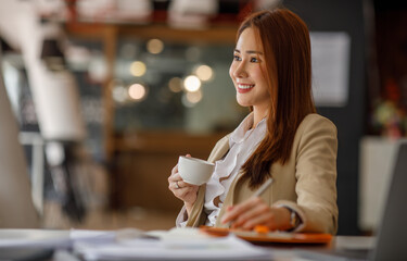 Cropped photo of Asian business woman holding coffee cup with a beverage during a coffee break at the workplace. Business concept