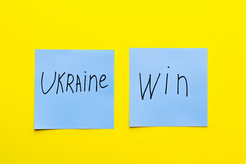 top view of blue papers with ukraine win lettering on yellow background.