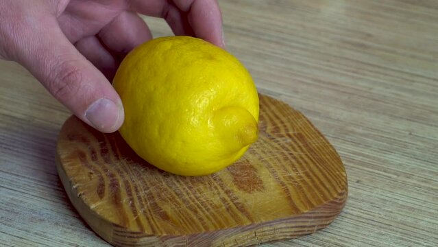 A man's hand holds a knife. Cuts a yellow lemon. tropical fruit. Preparing a drink. Close-up. dietary product. Vitamin C. Sour taste. Slow motion.