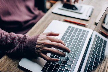 Unrecognizable male software developer typing program code on laptop keyboard using coworking connection while doing remote job, cropped IT professional creating web design during netbook projecting