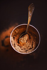 Top view of a jar filled with fragrant natural cocoa powder, which contains a teaspoon. A drink for breakfast. Quick instant coffee. Cinnamon.