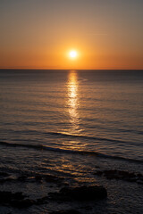 Obraz premium Sunset in calm waters of Atlantic ocean and clear sky