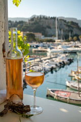 Cold rose wine in glass and bottle served on outdoor terrace in sunlights with view on old...