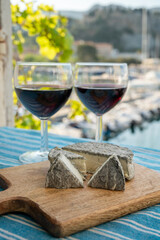 Summer party with red wine and cheeses on outdoor terrace with view on old fisherman's harbour with colourful boats in Cassis, Provence, France