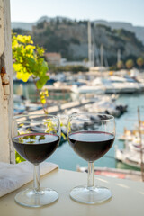 Drinking of red wine on outdoor terrace with view on old fisherman's harbour with colourful boats in Cassis, Provence, France