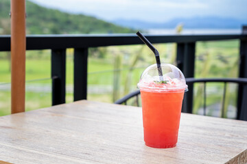 Refreshing drinks for summer, ice berry juice in a plastic cup with blurred green background. Organic for healthy, Perfect drink for summertime, and copy space for text. Holiday and healthy drink 