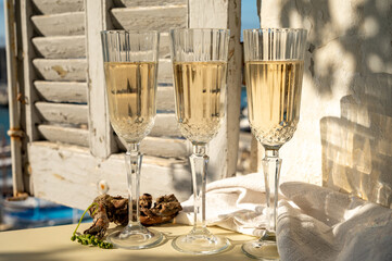 Three glasses of French champagne sparkling wine and view on colorful fisherman's boats in old harbour in Cassis, Provence, France