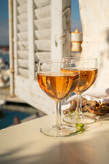 Summer party with cold rose wine in glass served on outdoor terrace in sunlights with view on old...