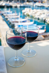 Drinking of red wine on outdoor terrace with view on old fisherman's harbour with colourful boats in Cassis, Provence, France