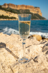 French champagne sparkling wine in glass and view on beach and mountains in Cassis, Provence, France