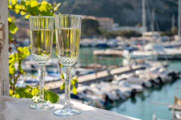 Two glasses of French champagne sparkling wine and view on colorful fisherman's boats in old harbour in Cassis, Provence, France