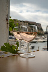 Rose wine in glasses served on outdoor terrace with view on old fisherman's harbour with colourful boats in Cassis, Provence, France