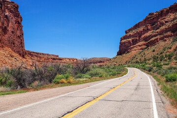 US road 128 winding through Utah desert between red cliffs on abeautiful day of spring. Scenic drive through American southwest. Riding a remote road.