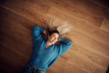 Top view of happy woman lying on the floor at her new home.