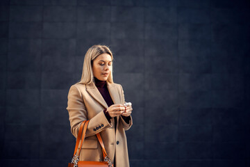 A woman in coat taking earphones from box.