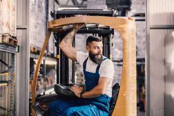A warehouse worker sitting in forklift and waiting for freight.