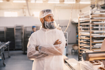 Fototapeta na wymiar A food factory worker posing next to a table with fresh cookies.