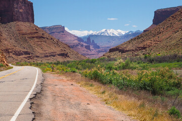La Sal Peak, Mount Waas, Castle Mountain covered in snow on distant horizon, viewed from canyon of Colorado River with US road 128 running through it. Scenic drive through American southwest.