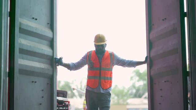 Dock manager or engineer worker in safety vest open the container door and inspector good inside in shipping yard. Import and export product. Manufacturing transportation and global business concept