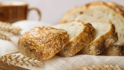Close up of sliced wheat bread on linen towel on wooden table, selective focus.