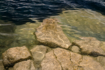 Nature background with big granite stones in transparent water on bottom.