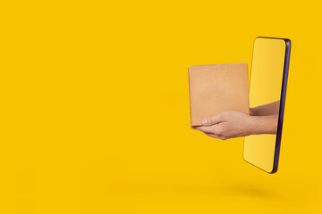 Male hands holding out parcel from modern smartphone on yellow background. Online shopping, service and delivery concept. - obrazy, fototapety, plakaty