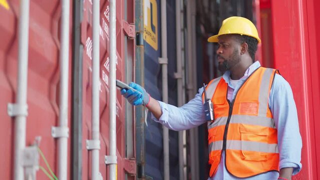 Dock worker man in safety vest holding barcode scanner and inspector the quality of container at shipping yard. Import and export product. Manufacturing transportation and global business concept
