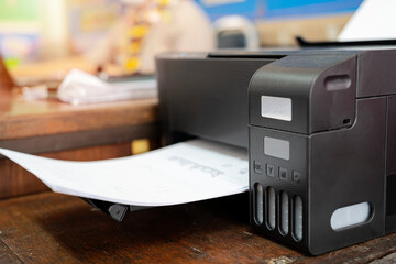 Teachers who are using a printer by ordering a print job via a laptop. - obrazy, fototapety, plakaty