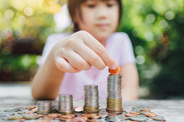 Little girl stacking coin for saving money for wealth and growth of business income financial...