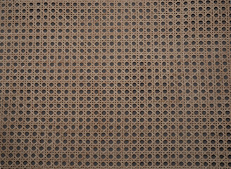 Image en gros plan d’un cannage traditionnel en rotin naturel, présentant un motif géométrique classique avec des croisillons entrelacés