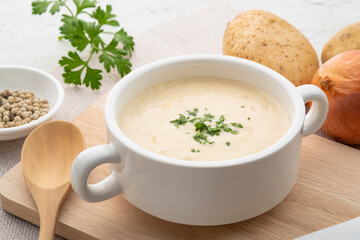 Fototapeta na wymiar Bowl of creamy potato soup on wooden plate
