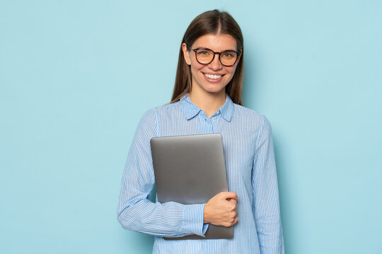 Smiling teacher in glasses and casual clothes holding laptop over blue copy space background