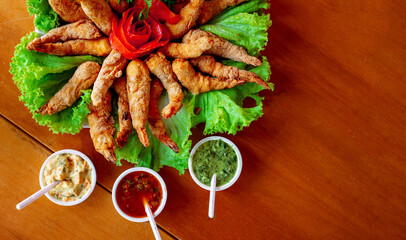 battered and fried shrimp on a large plate decorated with tomato and lettuce, accompanied by various sauces