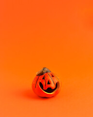 Decoration orange small smile Halloween pumpkin on orange blurred background and copy space. Holiday autumn concept backdrop.