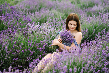 Beautiful girl hold bouquet purple lavender flowers in field. Female collect lavender. Woman in the lavender field. Enjoy the floral glade, summer. Down view. Close up