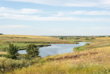 Fototapeta premium rural landscape of a field with a river on the background of a cloudy sky august ukraine