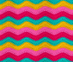 Seamless knitted pattern in the form of zigzags is crocheted with bright multi-colored threads. Acrylic baby yarn. African style.