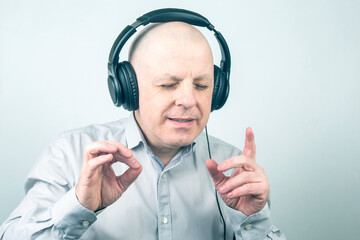 man with closed eyes listens to music with headphones on a light background