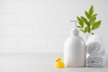 Obraz na płótnie Canvas Mockup of a white dispenser with a cosmetic product such as soap, shower gel, with a little duck and white towels