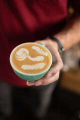 guy in a red t-shirt holding a green cup of coffee