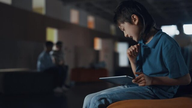 Focused boy using pad lose in online game. Pupil with gadget ignoring classmates