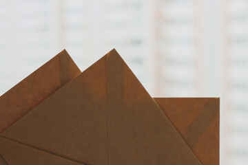Three closed brown craft envelopers corners on light blurred background, horizontal photo. Recycled paper, mail concept, blank envelopes for card or invitation