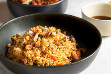 Thai fried rice with nuts and vegetables in a black bowl with soy sauce. Asian food concept. High quality photo