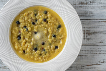 Plain oatmeal porridge with blueberries, butter, turmeric and honey in white plate