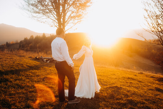 Wedding couple holding hands together at sunny day in mountains
