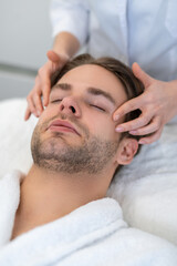 Fototapeta na wymiar Young man having face massage in a beauty salon