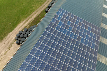 Aerial view of farm building with photovoltaic solar panels mounted on rooftop for producing clean...