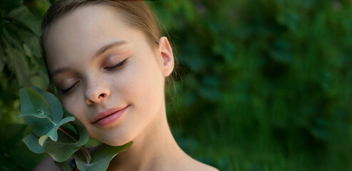 Beautiful cheerful smiling girl with eucalyptus leaf branch on green nature background.