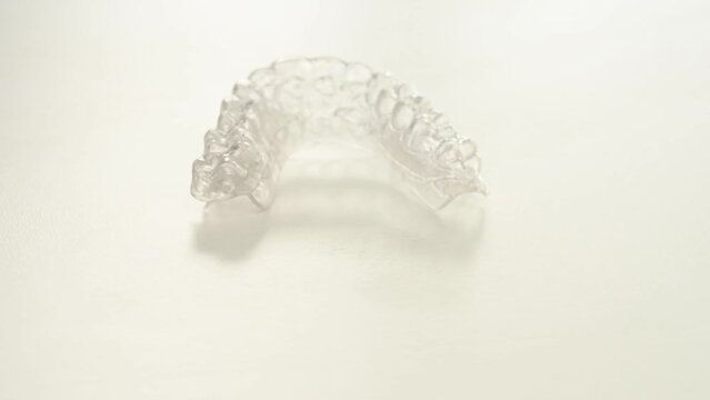 A transparent plastic aligner is spinning on a white background.